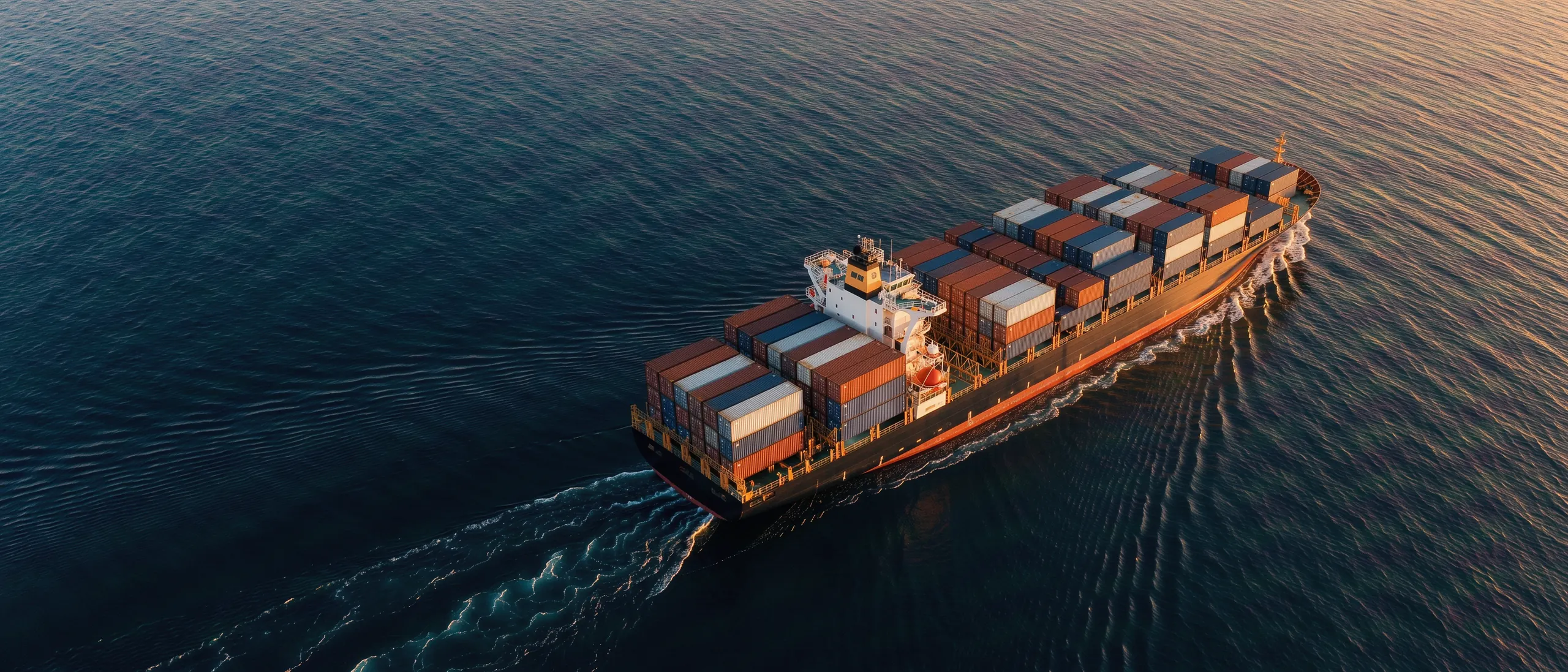 Beladenes Containerschiff auf offener See bei Sonnenuntergang